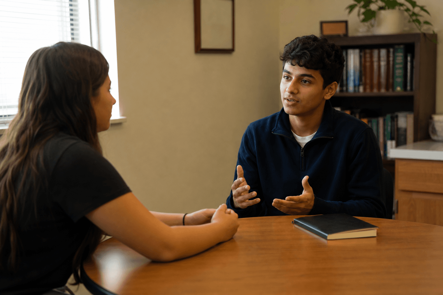 Two students practicing a one-on-one conversation in a quiet school office